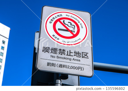 Yokohama cityscape, Japan. A "No Smoking Zone" sign near the Honmachi 5-chome intersection. The building on the left is Yokohama Second Joint Government Building. 135596802