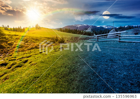 rural landscape in spring. day and night time change concept. haystack near fence on meadow with sun and moon at twilight. forest on rolling hills. mountain with snow tops. equality and shift template 135596963