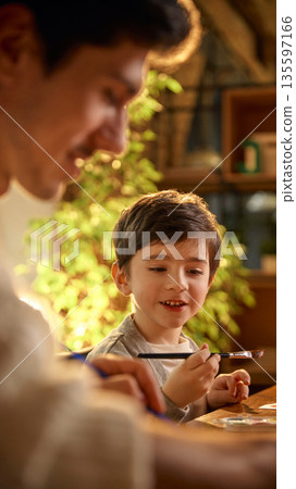 Adult and child painting with brushes and watercolor paints. 135597166