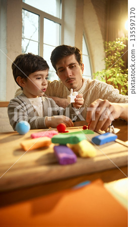 Father helping son explore creativity with colorful clay toys. 135597170