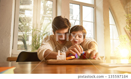 Dad helping his little son on clay art project at home. Dad helping his little son on clay art project at home. 135597184