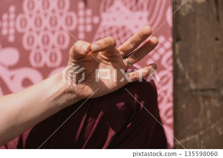 Hand Performing Yoga Gesture Against Patterned Mat Hand Performing Yoga Gesture Against Patterned Mat 135598060