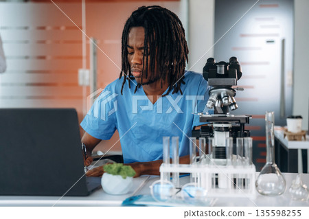 The microscope on the table. Black man doctor is in the office 135598255