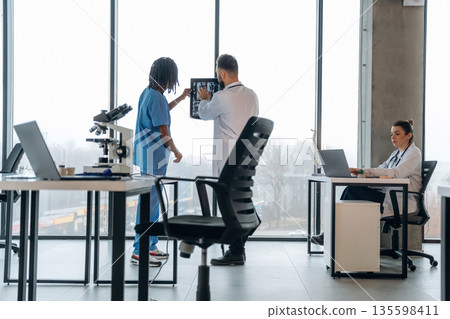 X-ray in hands, researching. Doctors are in the clinic X-ray in hands, researching. Doctors are in the clinic 135598411