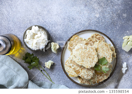 Healthy cauliflower fritters with cream cheese and parsley on rustic table Healthy cauliflower fritters with cream cheese and parsley on rustic table 135598554