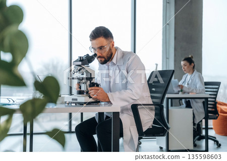 Modern technology, microscope is on table. Doctors are in the clinic Modern technology, microscope is on table. Doctors are in the clinic 135598603