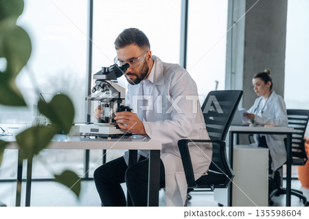 Modern technology, microscope is on table. Doctors are in the clinic Modern technology, microscope is on table. Doctors are in the clinic 135598604