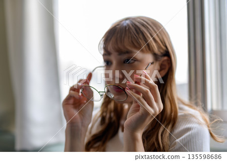 Woman adjusting her glasses Woman adjusting her glasses 135598686