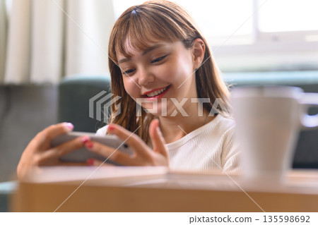Smiling woman operating a smartphone 135598692