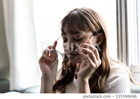 A woman takes off her glasses A woman takes off her glasses 135598696