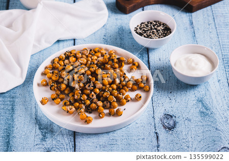 Appetizing roasted chickpeas with sesame seeds and herbs on a plate on the table Appetizing roasted chickpeas with sesame seeds and herbs on a plate on the table 135599022