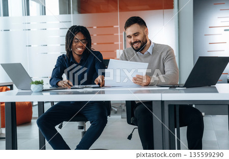 Some paperwork. Two men are in the office 135599290