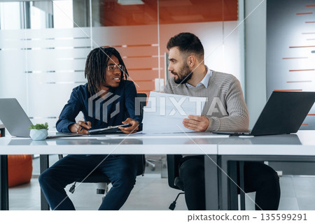 Some paperwork. Two men are in the office 135599291