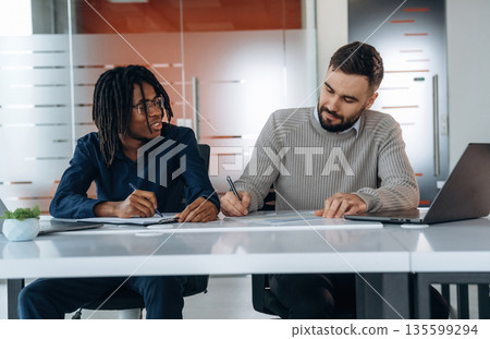 Some paperwork. Two men are in the office Some paperwork. Two men are in the office 135599294