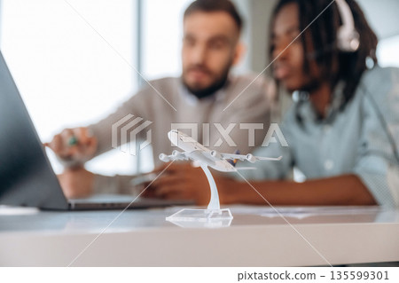 Close up view of little airplane model. Two men are working in the office 135599301