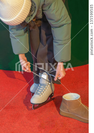 Closeup of person tying laces on ice skates focusing on the ice skates, preparing for ice skating. Concept of winter sport activity Closeup of person tying laces on ice skates focusing on the ice skates, preparing for ice skating. Concept of winter sport activity 135599585