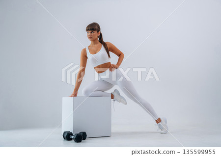 Ready for exercise, dumbbells on floor. Young sportive woman is in the studio 135599955