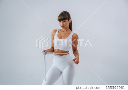 Diet conception, measuring tape. Young sportive woman is in the studio Diet conception, measuring tape. Young sportive woman is in the studio 135599961