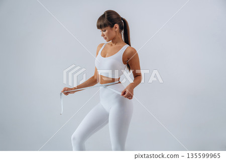 Diet conception, measuring tape. Young sportive woman is in the studio 135599965