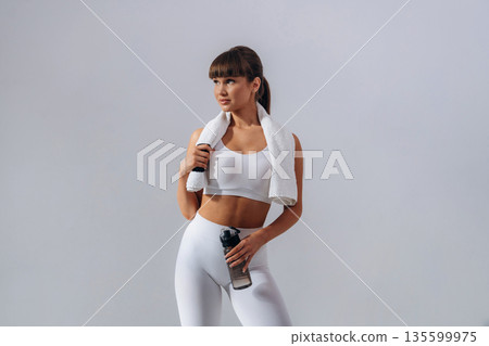 Against white wall. Young sportive woman is in the studio 135599975