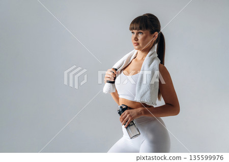 Fresh water in bottle. Young sportive woman is in the studio Fresh water in bottle. Young sportive woman is in the studio 135599976