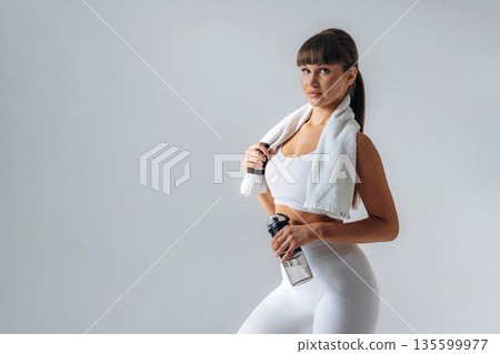 Towel on neck. Young sportive woman is in the studio 135599977