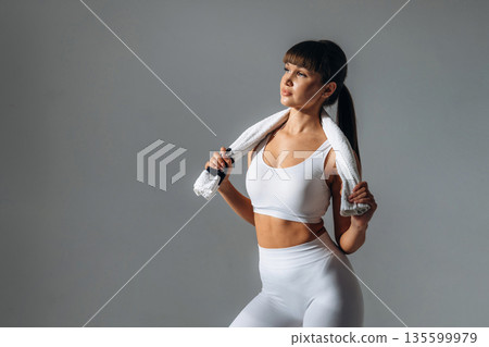 Towel on neck. Young sportive woman is in the studio 135599979