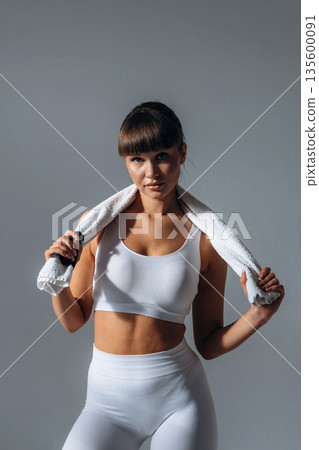 Towel on neck. Young sportive woman is in the studio 135600091