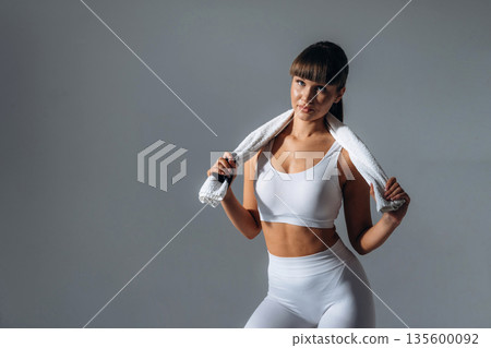 Towel on neck. Young sportive woman is in the studio 135600092