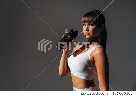 Drinking water, break. Young sportive woman is in the studio Drinking water, break. Young sportive woman is in the studio 135600102