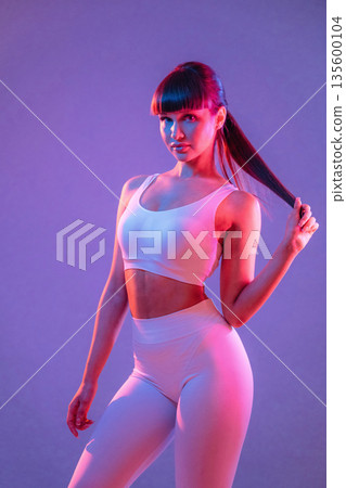 Athletic fitness body type, standing. Young sportive woman is in the studio Athletic fitness body type, standing. Young sportive woman is in the studio 135600104
