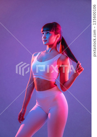 Athletic fitness body type, standing. Young sportive woman is in the studio Athletic fitness body type, standing. Young sportive woman is in the studio 135600106