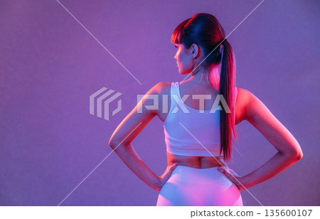 Back, standing and showing spine. Young sportive woman is in the studio Back, standing and showing spine. Young sportive woman is in the studio 135600107