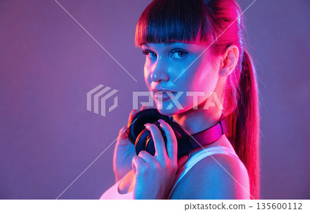 Headphones on the neck. Young sportive woman is in the studio 135600112