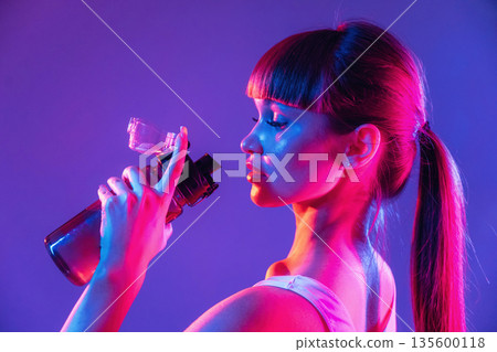Fresh water in bottle. Young sportive woman is in the studio Fresh water in bottle. Young sportive woman is in the studio 135600118
