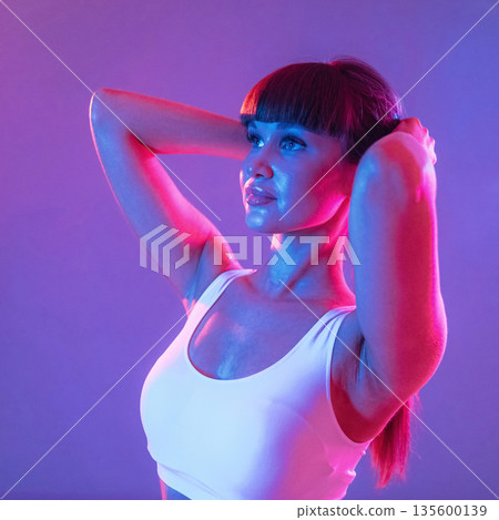 Touching her hair, standing and posing. Young sportive woman is in the studio 135600139