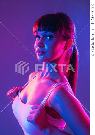 Touching the top, neon lighting. Young sportive woman is in the studio Touching the top, neon lighting. Young sportive woman is in the studio 135600158