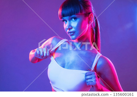 Neon lighting, showing the top. Young sportive woman is in the studio 135600161