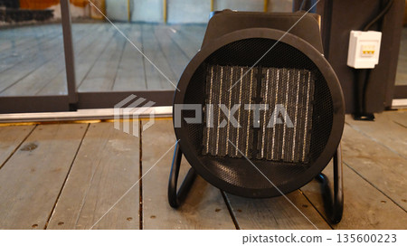 Portable electric space heater on wooden floor in modern interior 135600223