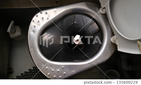 Stainless steel toilet bowl in small bathroom inside passenger train 135600229