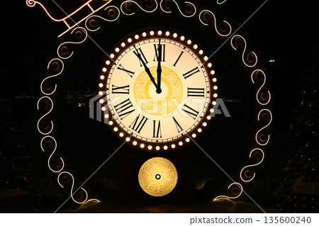 Vintage clock with Roman numerals showing midnight time close-up Vintage clock with Roman numerals showing midnight time close-up 135600240
