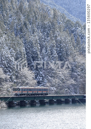 A local train on the Takayama Main Line running along the Hida River in winter scenery A local train on the Takayama Main Line running along the Hida River in winter scenery 135600297