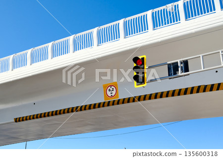 Modern overpass with traffic light and road sign, urban infrastructure, concrete bridge structure against blue sky Modern overpass with traffic light and road sign, urban infrastructure, concrete bridge structure against blue sky 135600318
