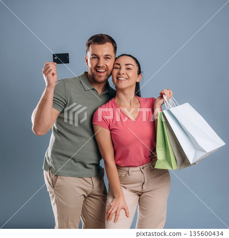 Black colored credit card, with shopping bags. Man and woman are in the studio 135600434