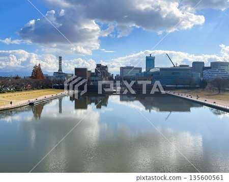 The cityscape of Toyama City, Toyama Prefecture, seen from Fugan Canal Kansui Park. The sky reflects off the water, creating a beautiful winter scene. 135600561