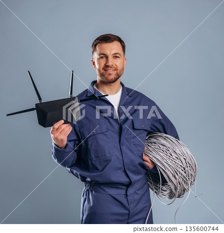 Modern wi-fi router and internet cables. Handsome man is against background Modern wi-fi router and internet cables. Handsome man is against background 135600744