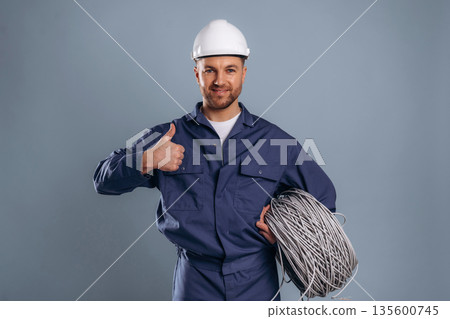 Showing thumb up, internet cables. Handsome man is against background Showing thumb up, internet cables. Handsome man is against background 135600745