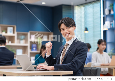 工作在辦公室的一個年輕商人 工作在辦公室的一個年輕商人 135600804