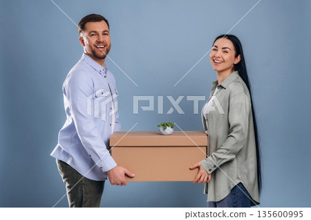 Positive, holding boxes, moving. Man and woman are in the studio Positive, holding boxes, moving. Man and woman are in the studio 135600995