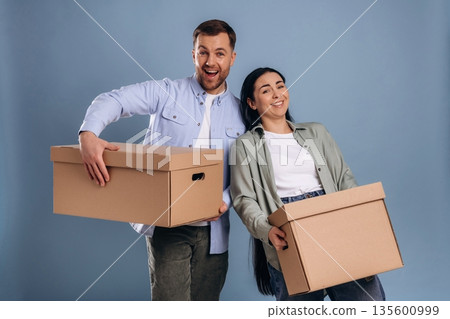 Together with boxes, moving. Man and woman are in the studio Together with boxes, moving. Man and woman are in the studio 135600999